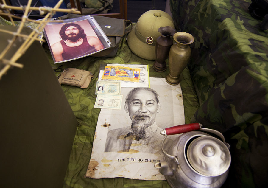 A series of papers and supplies sits on display before the listening juniors. safe for a portrait of Donald Dorsey in college, all the gears and pieces are remnents of the Vietnamese troops during the Vietnam war.