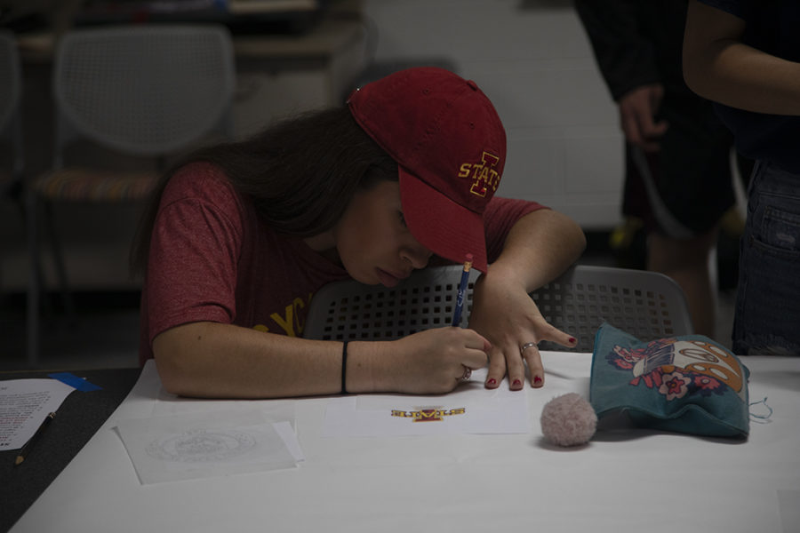 Showing of her future school’s merchandise, senior Nina Guerra works on tracing the logo for the Senior Signing Day banner.