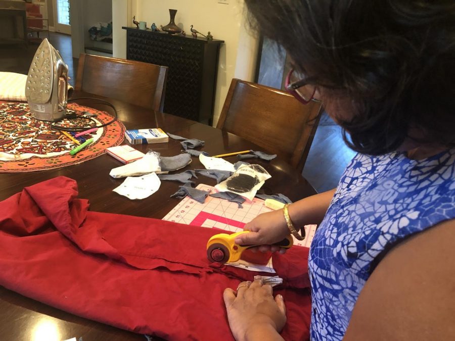 Deepika Basu Roy, mom of the writer, cuts fabric in the shape of masks using the Olson pattern before sewing them together with a sewing machine. The Olson pattern was designed by a doctor and is recommended by most medical professionals.