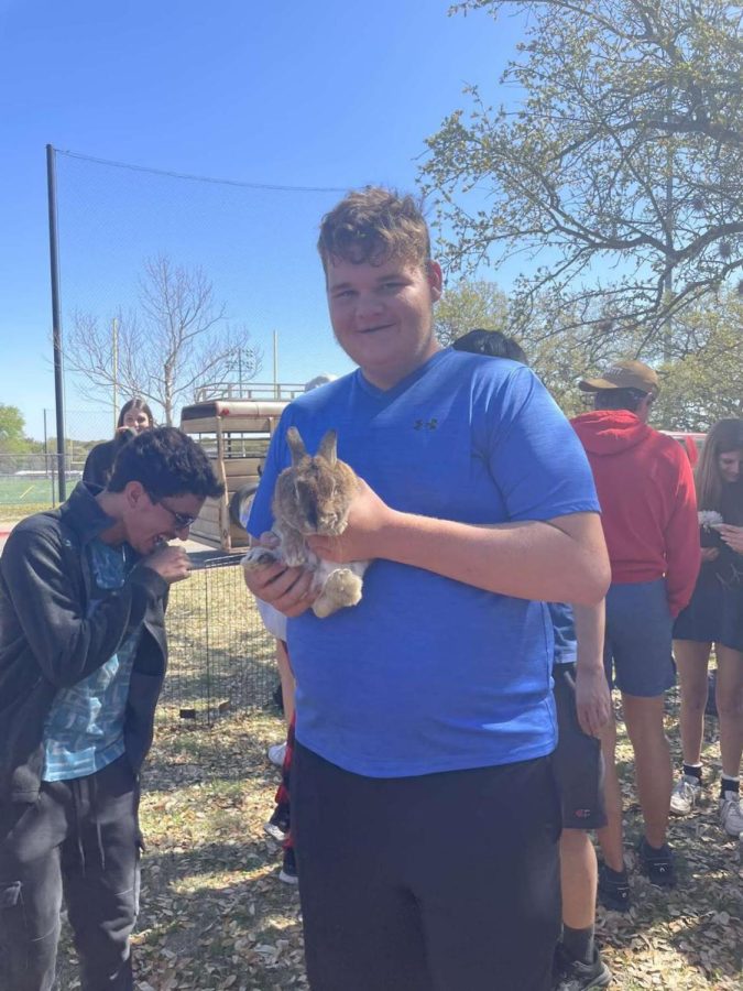 Junior Travis Suter holds one of the few male bunnies at the school’s petting zoo by the bus lane April 7. “I really liked feeding and playing with the animals, Travis said. It was a great experience!”