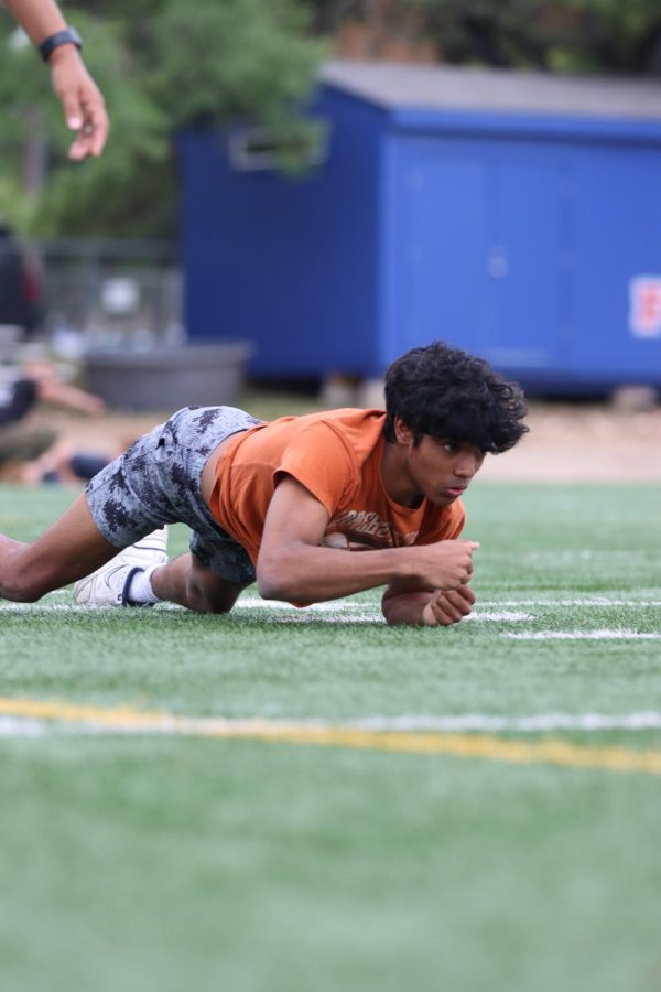 On the ground, junior Reuben Paul army crawls down the practice field in a military test March 31.