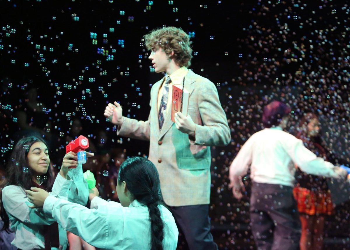 Senior Blaise Barbier wraps up the bubble bath scene as the narrator in Puffs Oct. 17 in the Black Box Theater. In the background, bubbles are produced by the ensemble team.